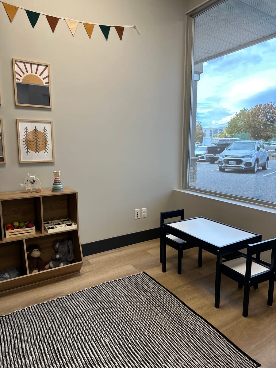 The kids' corner at The Den, with a toy shelf, a small table and chairs by the window